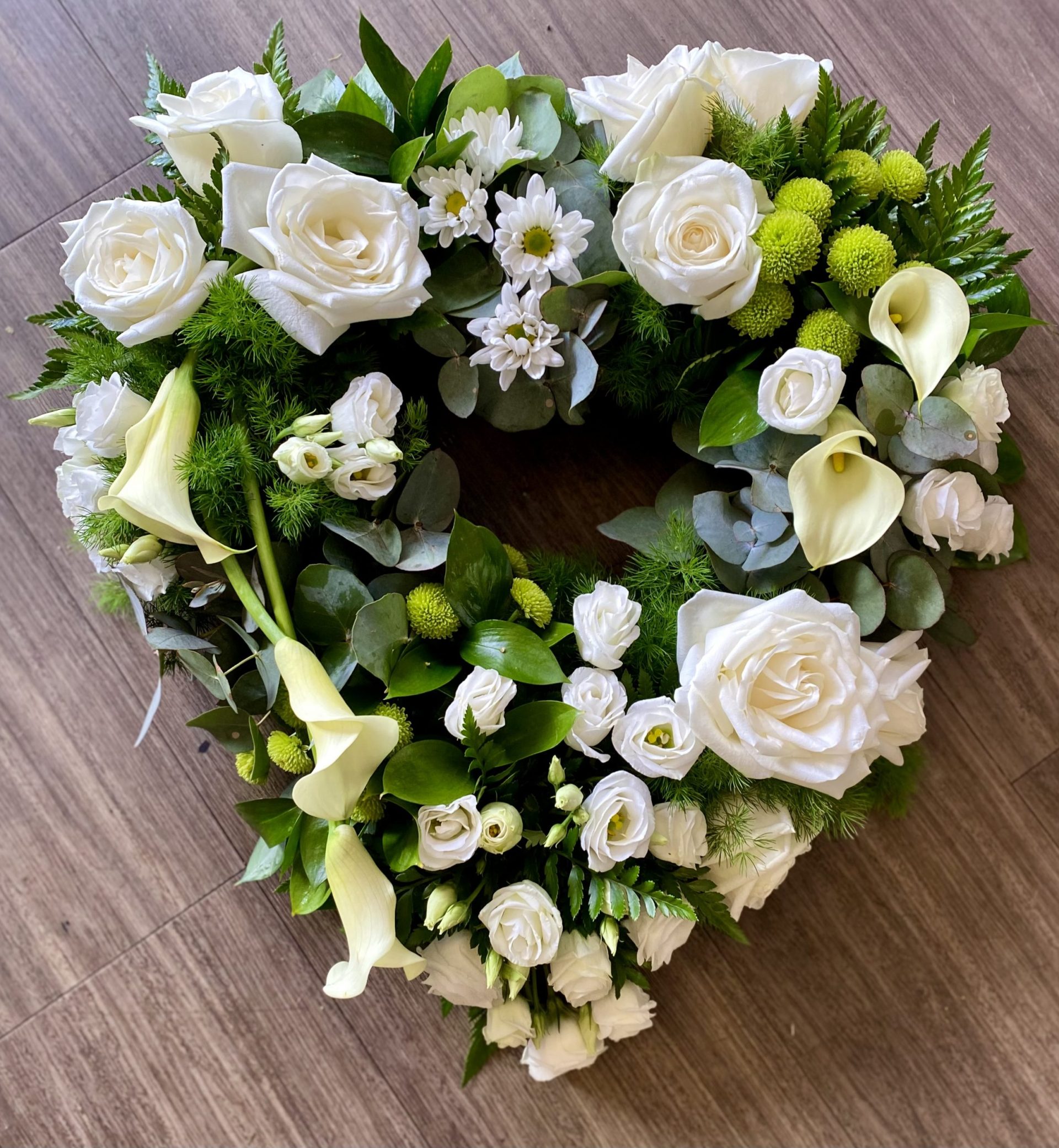 This elegant White heart Wreath is a thoughtful tribute, symbolising peace, purity, and remembrance. Crafted with a delicate mix of fresh flowers and lush greenery, it offers a serene and graceful statement to honour your loved one. - **Flowers:** White roses, lilies, chrysanthemums, and carnations for a timeless expression of purity and grace. Soft ferns, eucalyptus, and ivy intertwined to provide a natural, soothing backdrop. Same-day delivery available We understand the importance of expressing heartfelt condolences during difficult times. Our wreaths are hand-crafted with care, ensuring each arrangement is a meaningful tribute. 24 hours notice needed. Due to seasonal variations some items may be substituted to produce a display of equal quality and value.