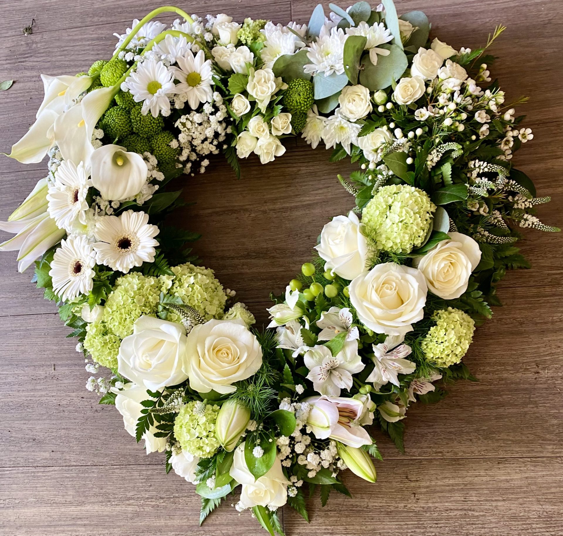 This elegant White heart Wreath is a thoughtful tribute, symbolising peace, purity, and remembrance. Crafted with a delicate mix of fresh flowers and lush greenery, it offers a serene and graceful statement to honour your loved one. - **Flowers:** White roses, lilies, chrysanthemums, and carnations for a timeless expression of purity and grace. Soft ferns, eucalyptus, and ivy intertwined to provide a natural, soothing backdrop. Same-day delivery available We understand the importance of expressing heartfelt condolences during difficult times. Our wreaths are hand-crafted with care, ensuring each arrangement is a meaningful tribute. 24 hours notice needed. Due to seasonal variations some items may be substituted to produce a display of equal quality and value.