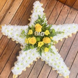 A massed star tribute is subtle yet striking set off with a lovely spray of flowers in the centre. Approximately 2ft. 24 hour notice needed. Edging ribbon & central spray, in your choice of colour Due to seasonal variations some items may be substituted to produce a display of equal quality and value. Professionally arranged by our expert florists with care. Delivered by hand by our own driver. Click & collect is also available